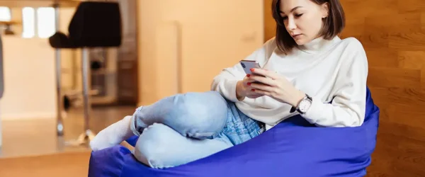 girl relaxing on a bean bag, using her publicmobile service to contact friends